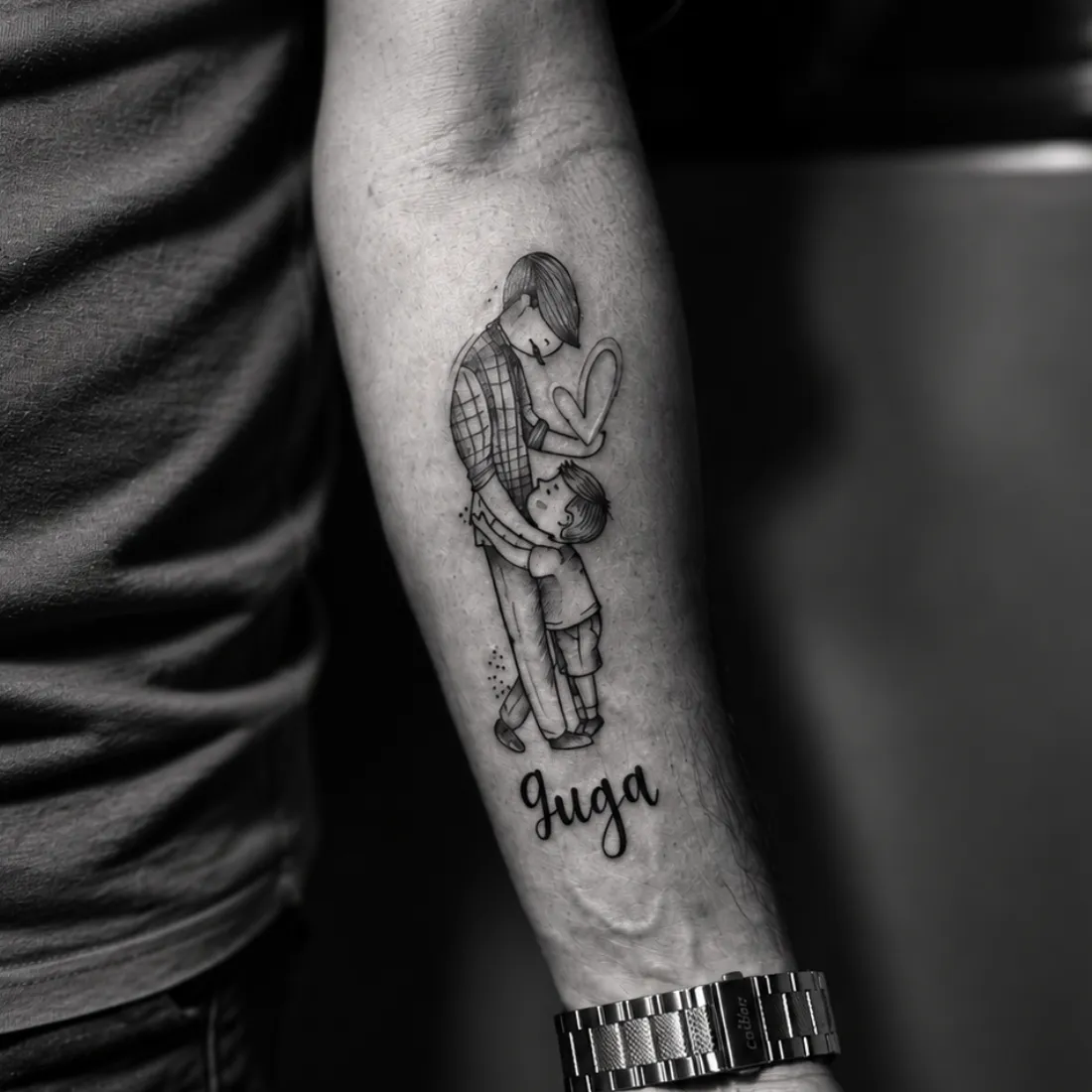 Tatuagem delicada de pai abraçando o filho com o nome Guga escrito abaixo, no antebraço