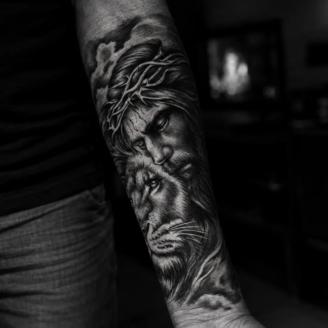 Tatuagem realista em preto e cinza de Cristo com coroa de espinhos e um leão no antebraço