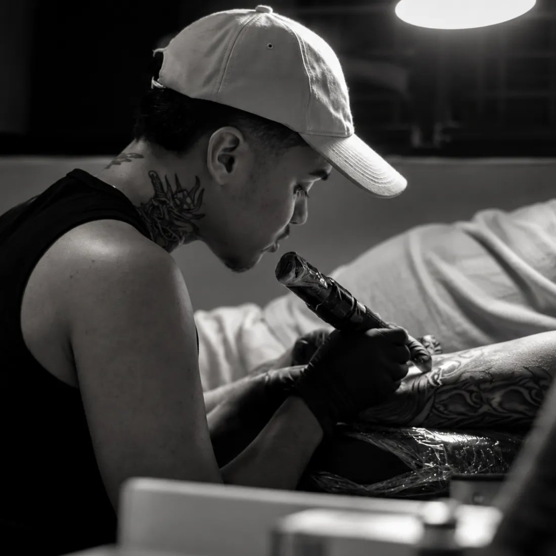 Iure Gabriel tatuando durante uma sessão no estúdio, em fotografia preto e branco